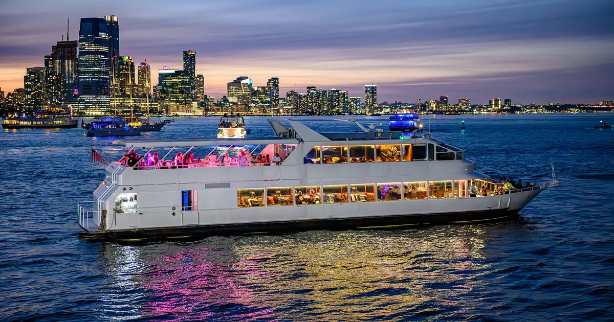 The dinner-cruise boat Louisa of the Seas lit up on New York Harbor at dusk with the Jersey City skyline behind