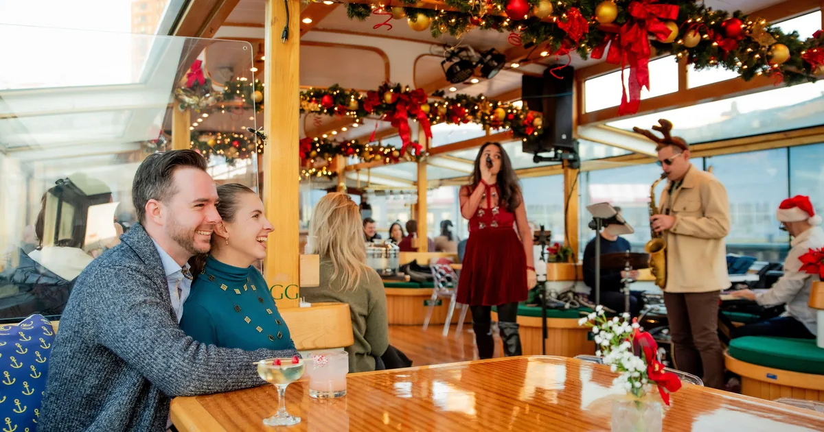 Guests at a table in the decorated salon of a Classic Harbor Line yacht with garlands and a wreath, the harbor outside